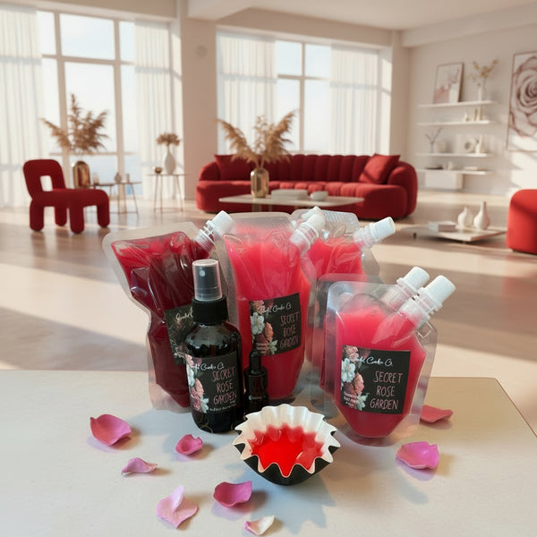 Bouquet of red squeezable wax melt bottles and a black bottle on a table with pink petals, against a neutral wall.