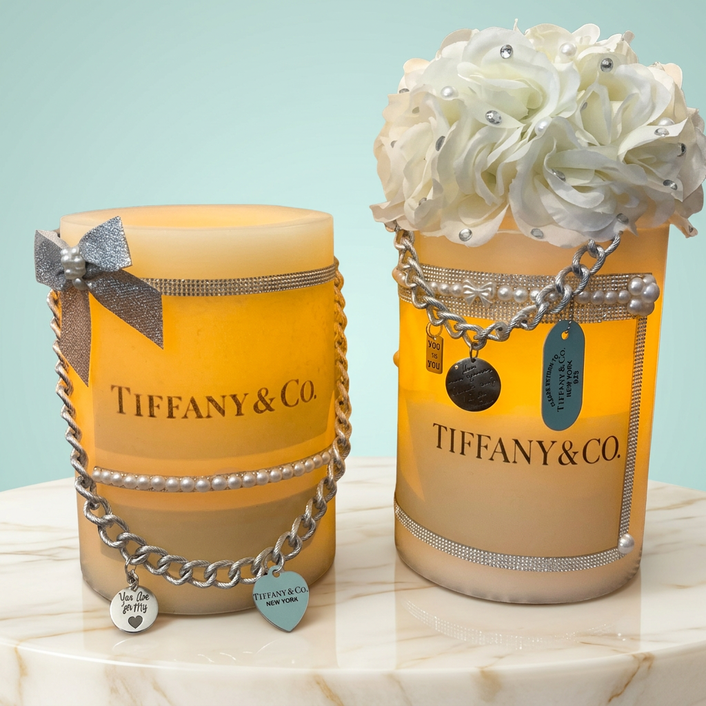Two decorated LED pillar candles with silver embellishments in a pale aqua studio setting