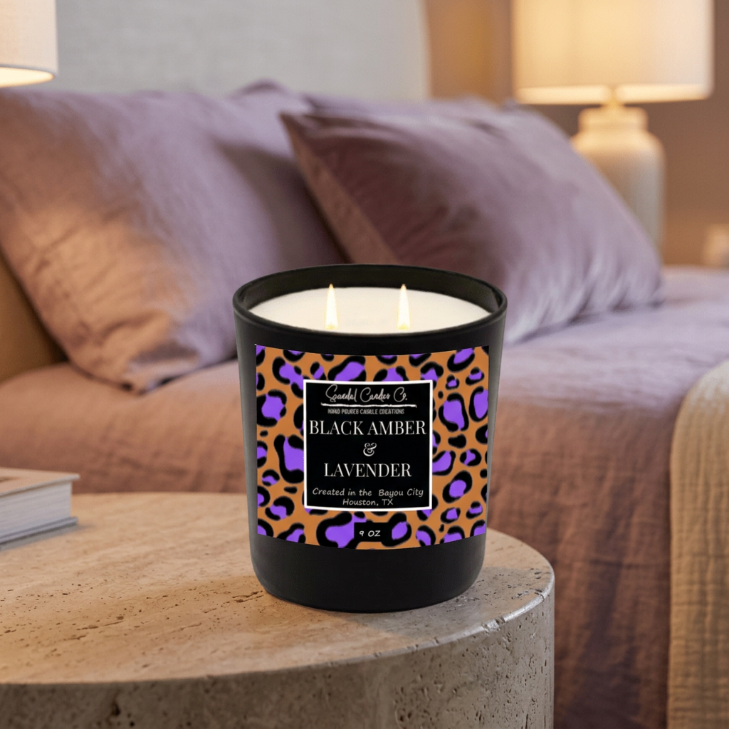 Black Amber & Lavender candle burning on a stone side table in a softly lit bedroom.
