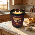Butter Me Up honey-buttered-rolls candle with a burgundy and honey-gold label, styled with rolls and cinnamon butter