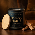 Havana Nights matte black candle with a natural wooden lid on dark wood with warm amber lighting and sandalwood.