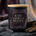 Angled view of Iced Vanilla Woods candle with Velvet Ember label and wooden lid beside lavender and textured wood.